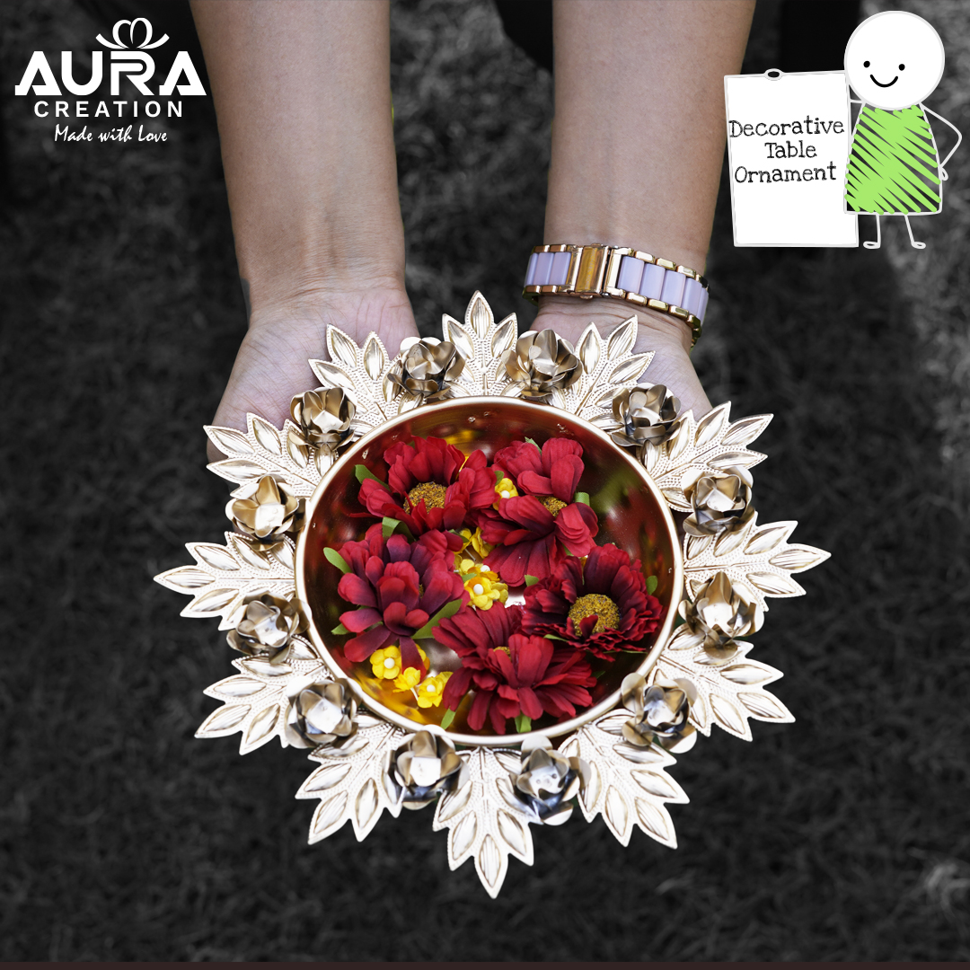 A decorative metal urli bowl filled with red flowers